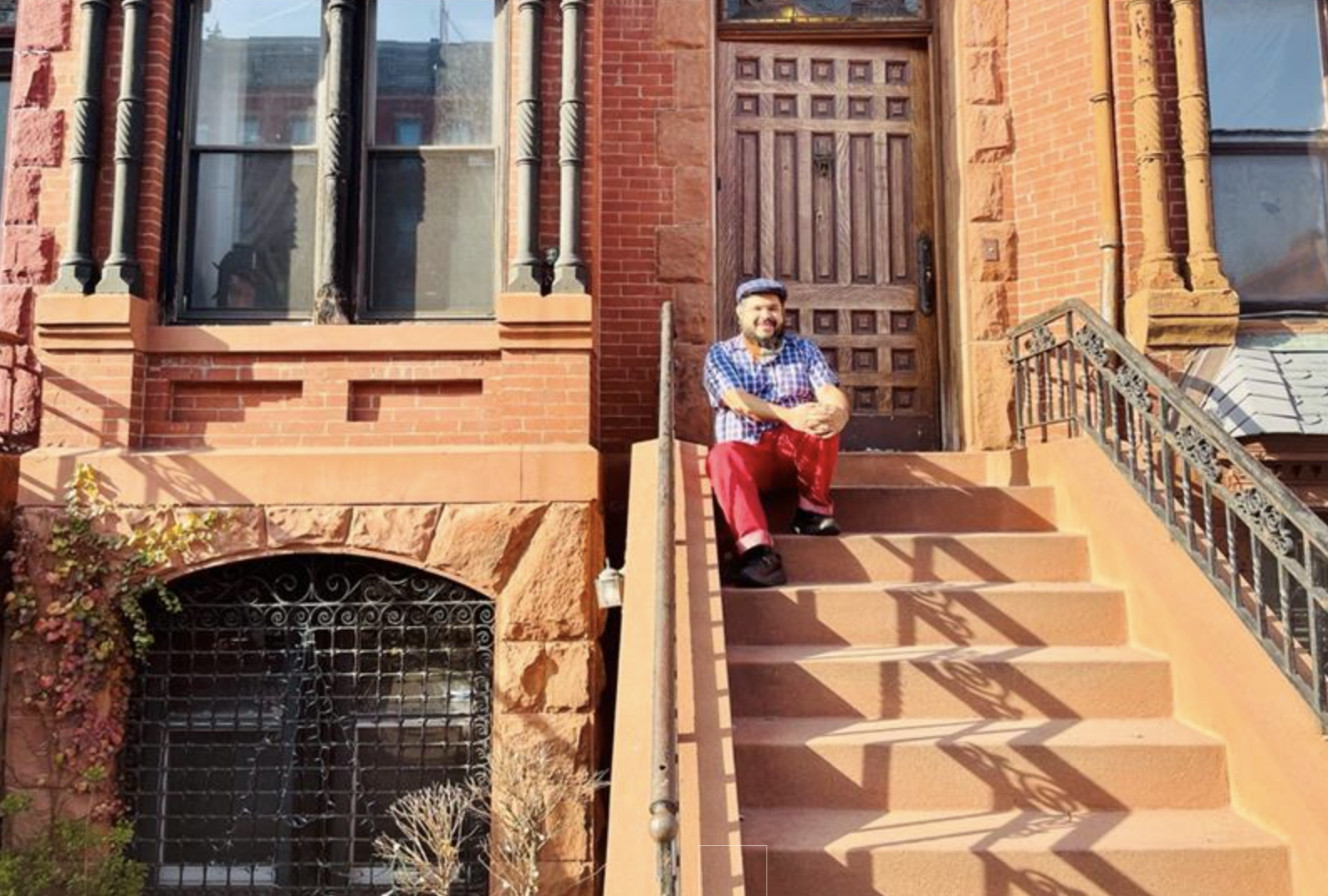 Monxo López sitting on the steps in front of a brownstone